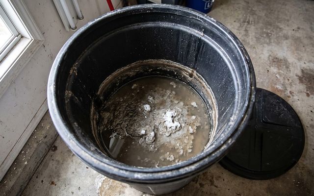 dirty sludge and standing water inside an open brine tank before cleaning