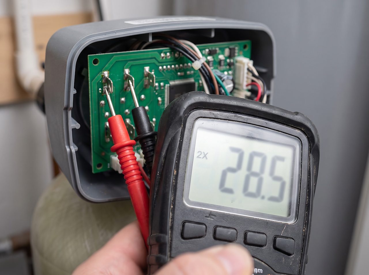 multimeter probes testing voltage on a softener control board during troubleshooting