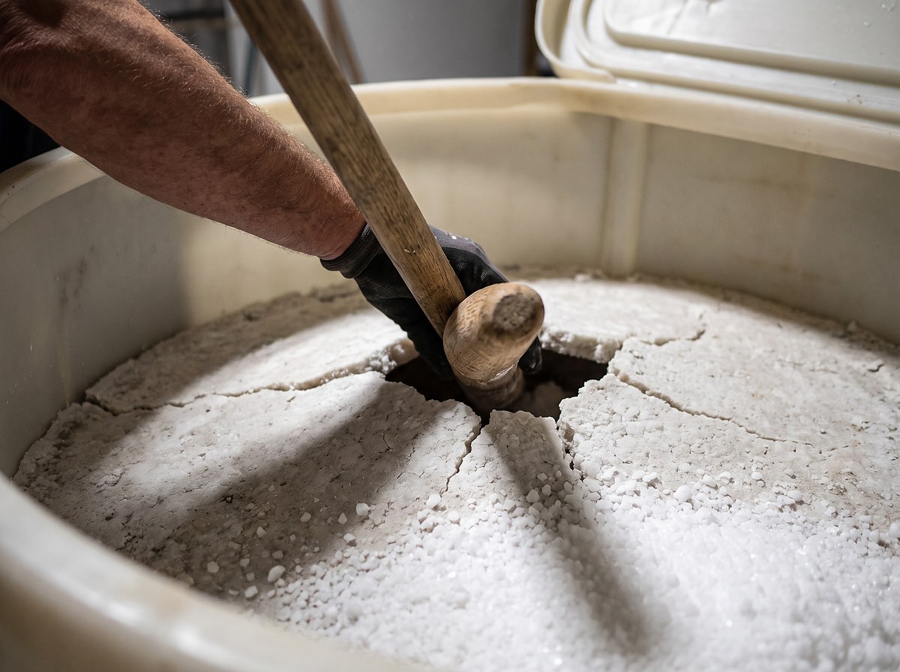 a wooden handle pressed into brine tank salt to test for a hardened crust
