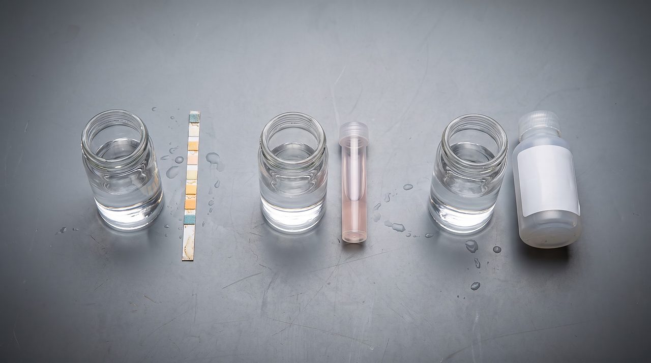 three water samples laid out beside a test strip, vial, and sample bottle