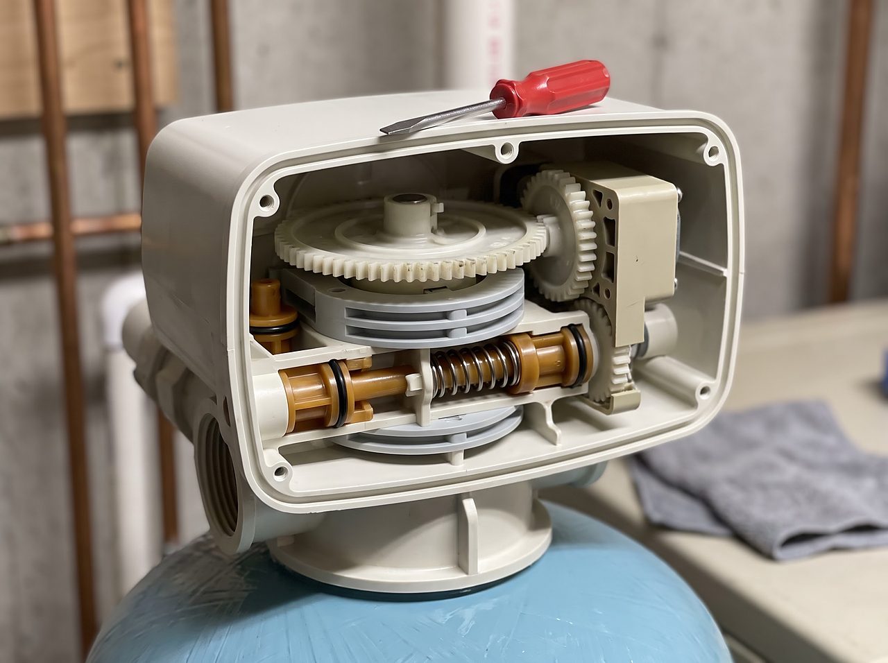 open water softener control valve showing internal gears, pistons, and seals during repair
