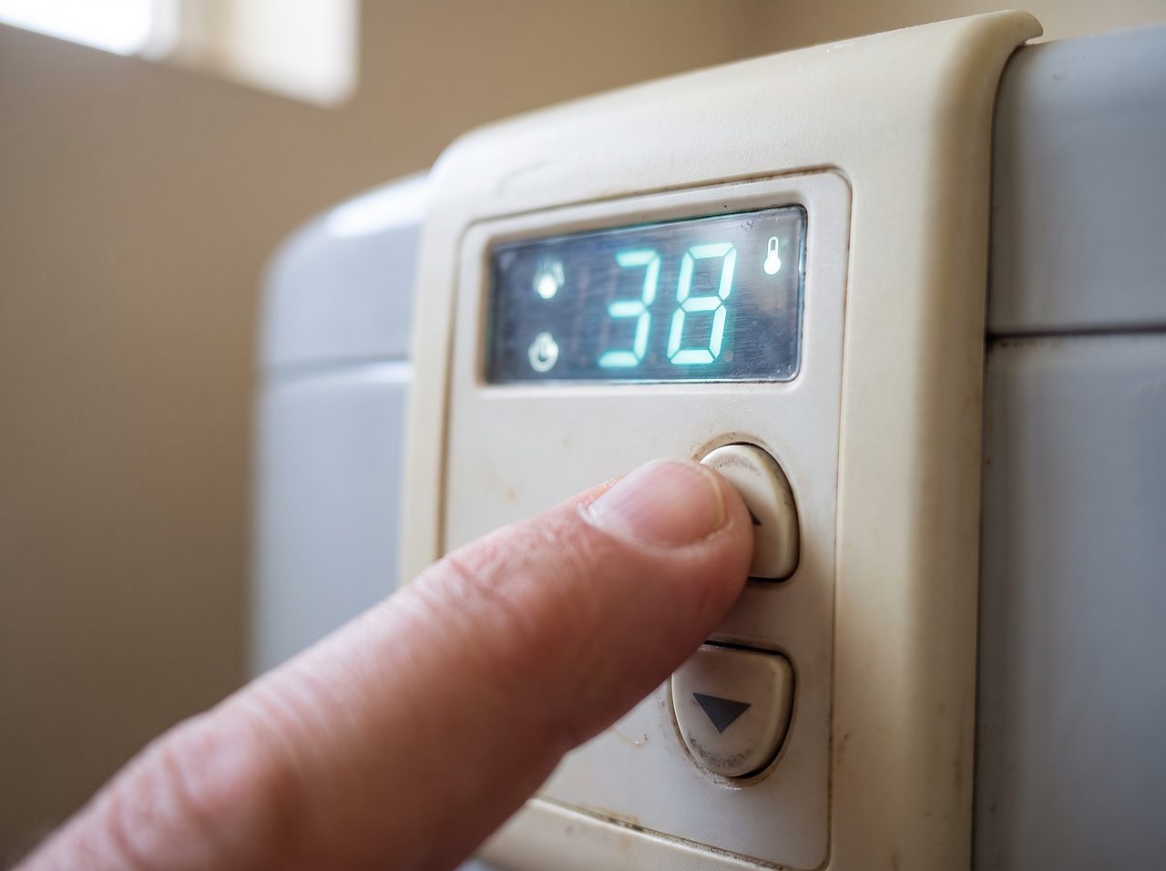 close-up of a finger adjusting a hardness number on a softener control display